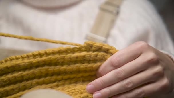 若い白人女性のクローズアップは、毛糸が毛糸製品を編んでいる間に間違いを犯すことを結ぶ — ストック動画