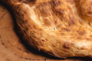 Fırında kızartılmış khachapuri ahşap bir tahtanın üzerinde yatıyor.