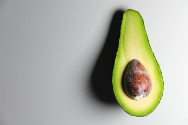 Beyaz bir masada yarım bir avokado. kontrastlı atış yumuşak odak