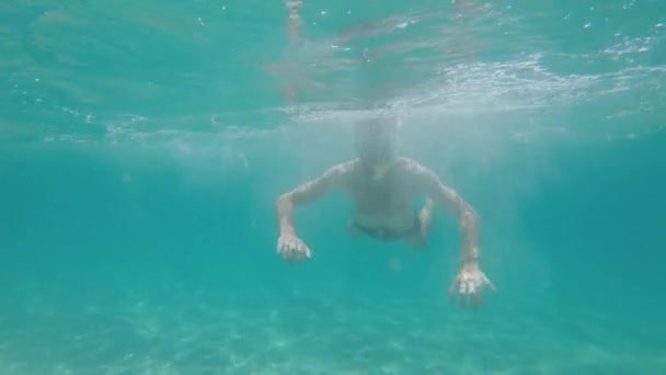 Hombre de barba caucásica en una máscara con un snorkel nada libremente en aguas poco profundas en el mar bajo el agua. Buceando en un día soleado — Vídeos de Stock