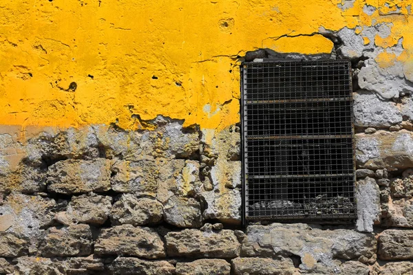 Pared amarilla y ventana con barras — Foto de Stock