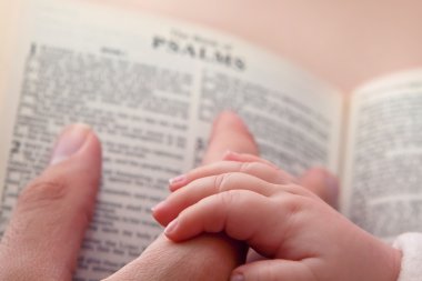Bebek baba parmak üzerinde İncil tutan