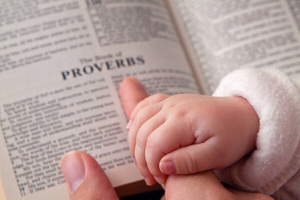 Baby Holding Dad Finger on Bible