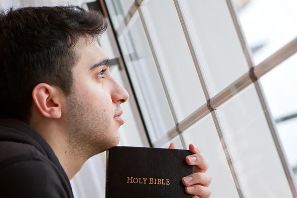 Hombre sosteniendo la Biblia mirando por la ventana — Foto de Stock