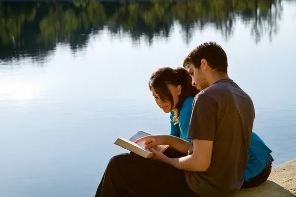 Couple lisant la Bible près d'un lac — Photo