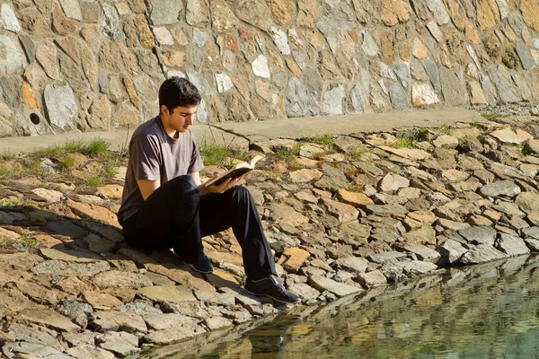 Hombre leyendo la Biblia por el lago — Foto de Stock