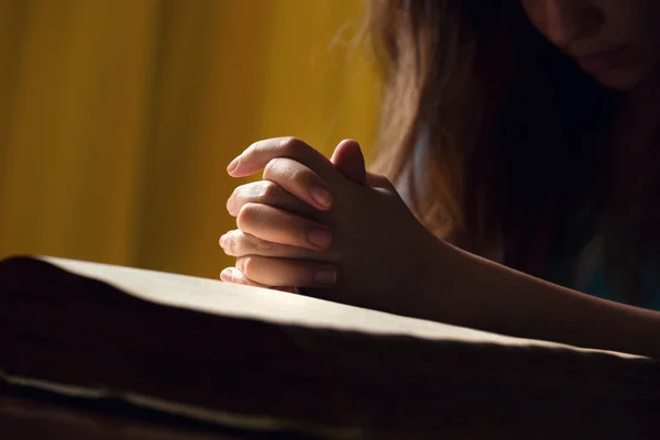 Ragazza che prega con le mani sulla Bibbia — Foto Stock