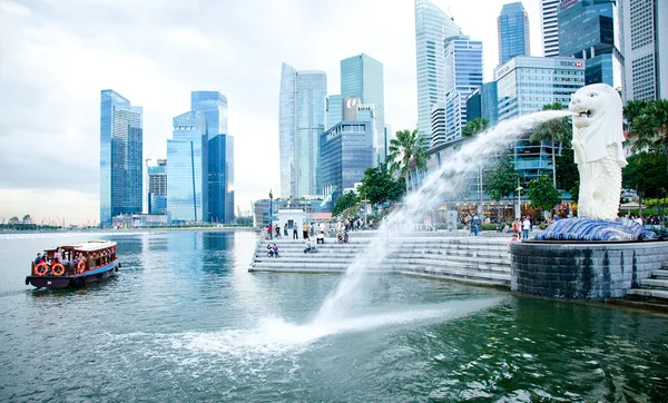 SINGAPORE-DEC 29: The Merlion fountain spouts water in front of the Singapore skyline — Stock Photo, Image