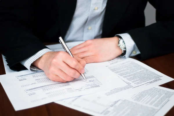 Zakenlieden invullen van bepaalde documenten op een bureau. — Stockfoto