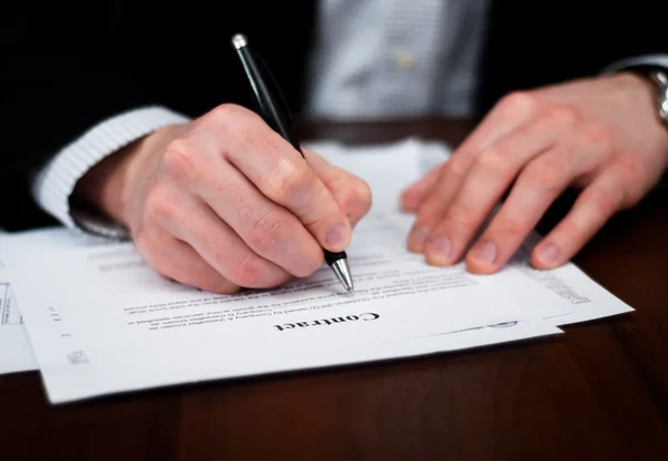Des hommes d'affaires remplissent un contrat sur table . Photos De Stock Libres De Droits