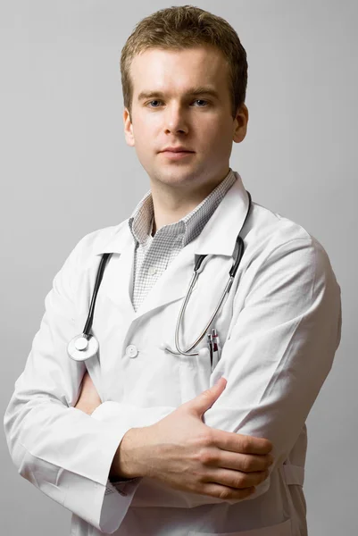 Junger Arzt auf grauem Hintergrund — Stockfoto