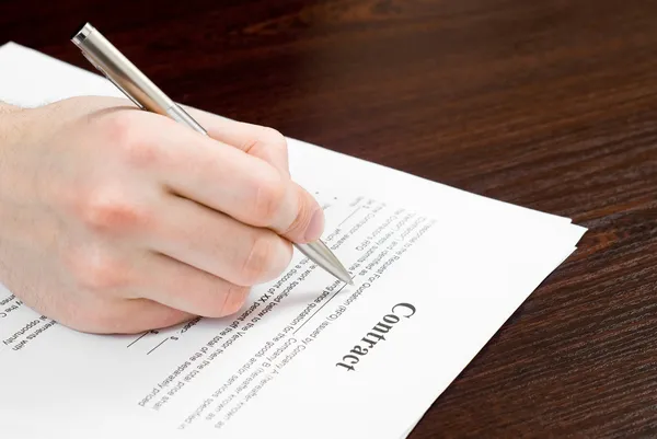 Male hand filling out and signing contract — Stock Photo, Image
