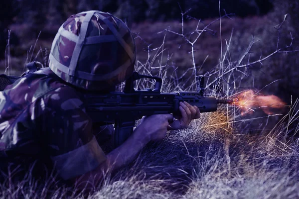 Young soldier with gun shooting in the dark — Stock Photo, Image