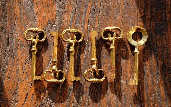 六黄铜钥匙在老黑暗的木背景 — 图库照片