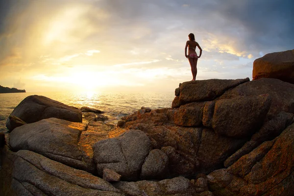 Mujer de pie sobre una roca y mirando al horizonte sobre el mar —  Fotos de Stock