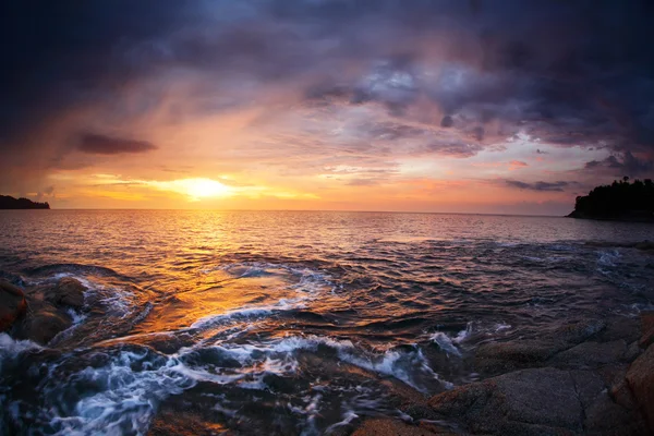 Skaliste wybrzeże i morze z falami o zachodzie słońca — Zdjęcie stockowe