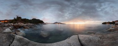 alacakaranlık bir kayalık sahil şeridi ve hareketli bulanık deniz yüzeyi Panoraması. Phuket, Tayland