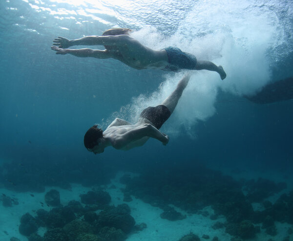 Two men gliding in a sea after jump