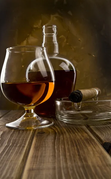 Glass and bottle with a cigar — Stock Photo, Image