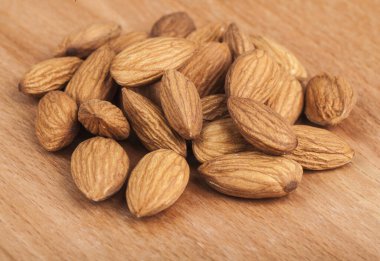 Tahta masadaki bademler. Tahta arka planda bir grup badem. Tasarım ayrıntıları. Tasarım elemanları. Makro. Tam odaklanma. Kartvizitler, kartpostallar ve posterler için arka plan. Gıda nesnesi tasarımı. 