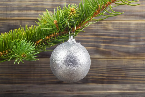 圣诞树的绿色枝条 木制桌子上挂着一个银球 圣诞树的枝条 有一个木制背景上的银球 设计的细节 设计元素 全神贯注名片 明信片和海报的背景 — 图库照片