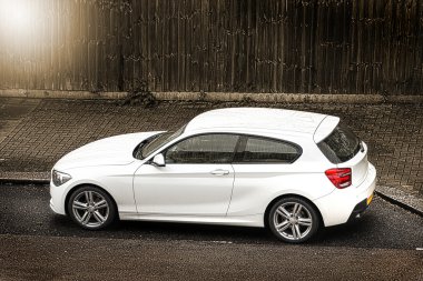 Beyaz hatchback araba sokakta park edilmiş.