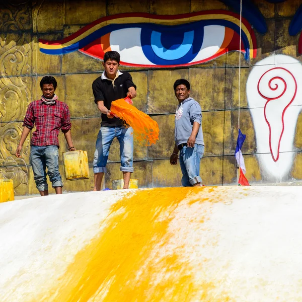 Mann wirft orangefarbene Farbe auf Boudhanath Stupa — Stockfoto