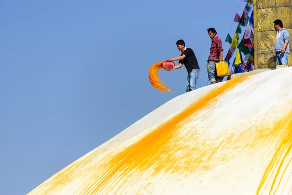 Homem jogando tinta laranja em Boudhanath stupa — Fotografia de Stock