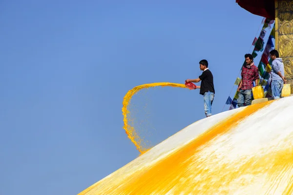 Man throwing orange paint on Boudhanath stupa — Stock Photo, Image