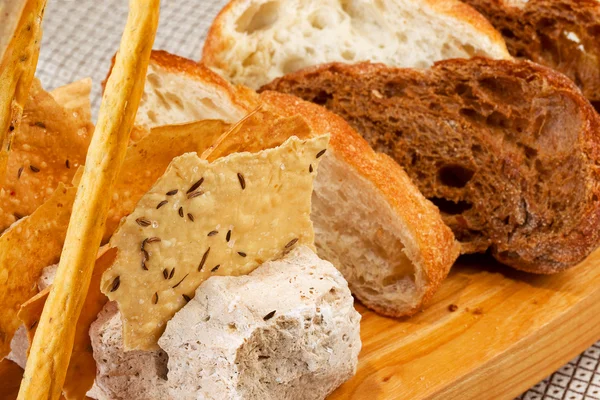 Assortment of baked bread on wooden plate — Stock Photo, Image