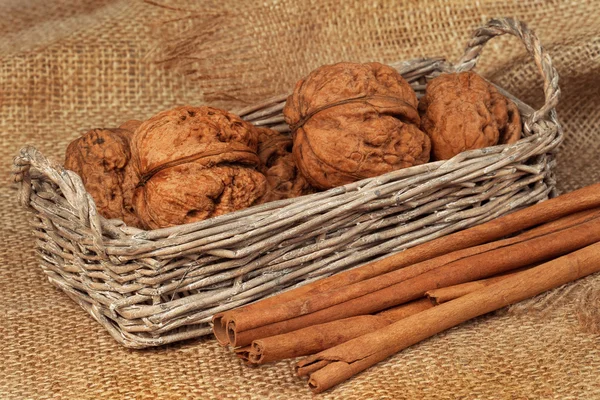 Walnuts in a wicker basket and cinnamon on sacking — Stock Photo, Image