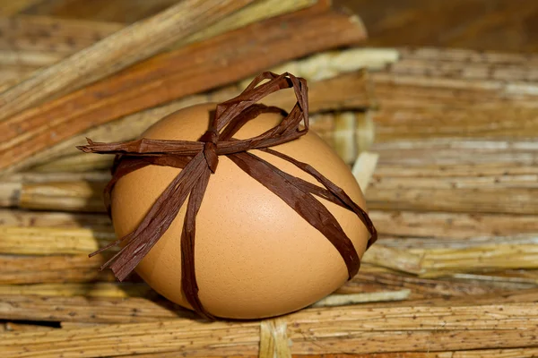 Velikonoční vajíčko s lukem na pozadí ze slámy — Stock fotografie