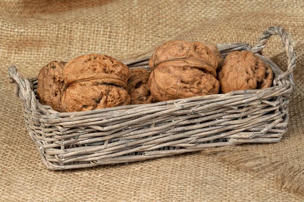 Орехи в плетеной корзине на мешке — стоковое фото