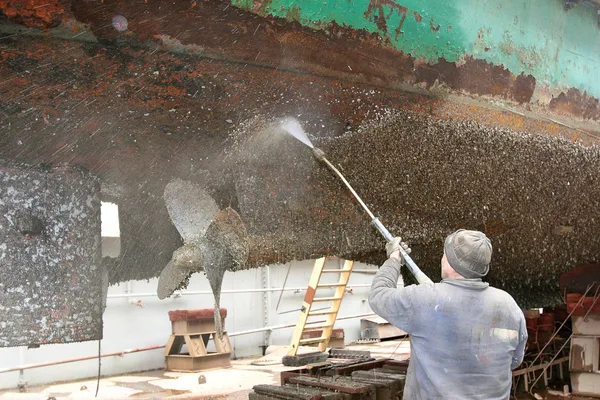 Work in dry dock with water jet cleans the bottom of the ship fr — Stock Photo, Image