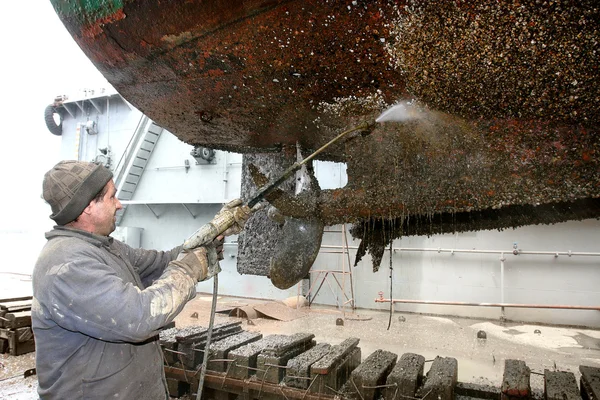 Робота в сухому доці з водяним струменем очищає дно корабля. — стокове фото