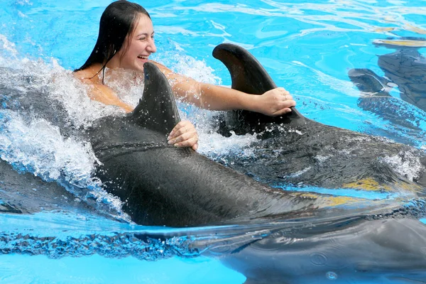 Beautiful young happy girl laughs and swims with dolphins in the — Stock Photo, Image