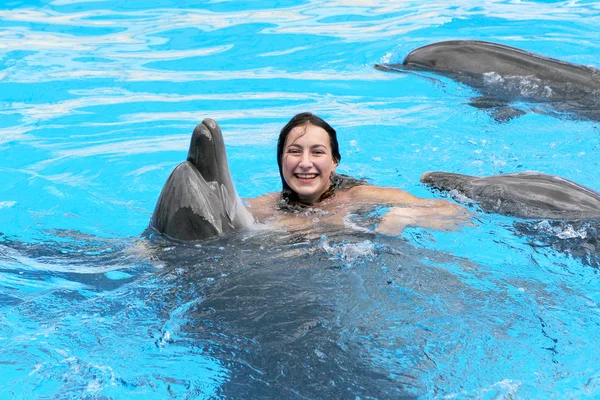 Feliz hermosa joven se ríe y nada con delfines en blu — Foto de Stock