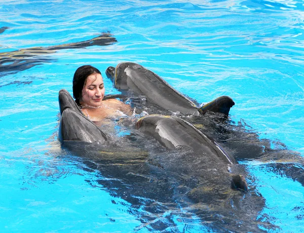 Menina bonita feliz ri e nada com golfinhos em blu — Fotografia de Stock