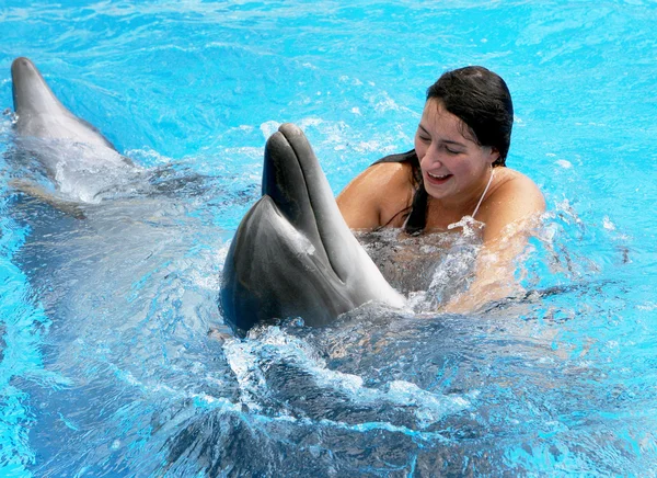 Feliz hermosa joven se ríe y nada con delfines en blu — Foto de Stock