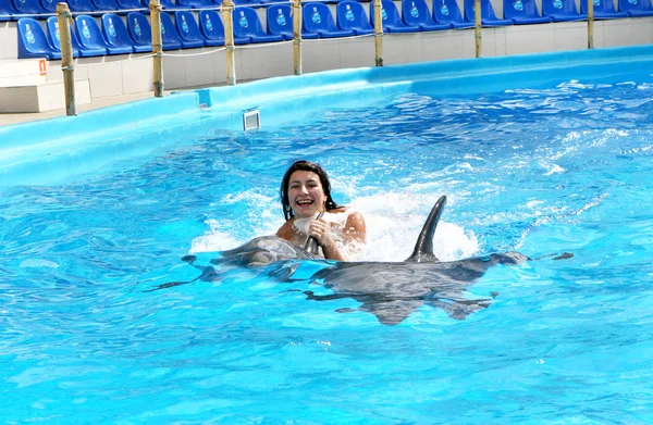 Feliz hermosa joven se ríe y nada con delfines en blu — Foto de Stock