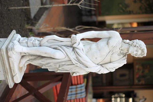 Klassisk sten skulptur av en ung manlig musiker med naken överkropp och ett koger med pilar — Stockfoto