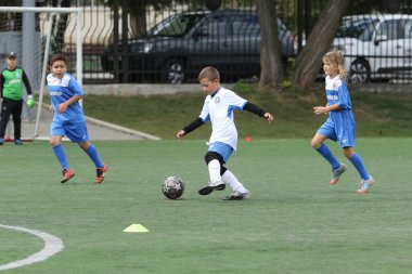 ODESSA, UKRAINE - 25 Eylül 2021: Küçük çocuklar, küçük çocuklar spor şampiyonası kasabasında yapay sahada futbol oynuyorlar. Çocuk sporları sağlıklı yaşam tarzıdır. Spor çocukları futbol oyuncuları