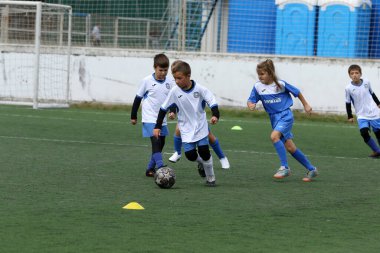 ODESSA, UKRAINE - 25 Eylül 2021: Küçük çocuklar, küçük çocuklar spor şampiyonası kasabasında yapay sahada futbol oynuyorlar. Çocuk sporları sağlıklı yaşam tarzıdır. Spor çocukları futbol oyuncuları