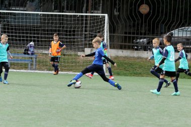ODESSA, UKRAINE - 25 Eylül 2021: Küçük çocuklar, küçük çocuklar spor şampiyonası kasabasında yapay sahada futbol oynuyorlar. Çocuk sporları sağlıklı yaşam tarzıdır. Spor çocukları futbol oyuncuları