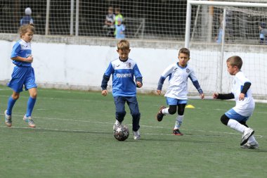 ODESSA, UKRAINE - 25 Eylül 2021: Küçük çocuklar, küçük çocuklar spor şampiyonası kasabasında yapay sahada futbol oynuyorlar. Çocuk sporları sağlıklı yaşam tarzıdır. Spor çocukları futbol oyuncuları