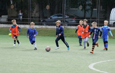 ODESSA, UKRAINE - 25 Eylül 2021: Küçük çocuklar, küçük çocuklar spor şampiyonası kasabasında yapay sahada futbol oynuyorlar. Çocuk sporları sağlıklı yaşam tarzıdır. Spor çocukları futbol oyuncuları