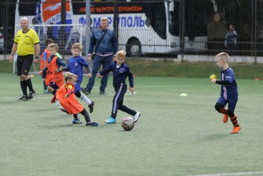 ODESSA, UKRAINE - 25 Eylül 2021: Küçük çocuklar, küçük çocuklar spor şampiyonası kasabasında yapay sahada futbol oynuyorlar. Çocuk sporları sağlıklı yaşam tarzıdır. Spor çocukları futbol oyuncuları