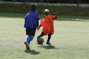 ODESSA, UKRAINE - 25 Eylül 2021: Küçük çocuklar, küçük çocuklar spor şampiyonası kasabasında yapay sahada futbol oynuyorlar. Çocuk sporları sağlıklı yaşam tarzıdır. Spor çocukları futbol oyuncuları