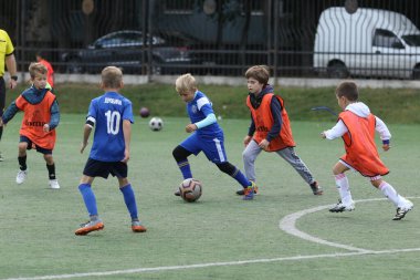 ODESSA, UKRAINE - 25 Eylül 2021: Küçük çocuklar, küçük çocuklar spor şampiyonası kasabasında yapay sahada futbol oynuyorlar. Çocuk sporları sağlıklı yaşam tarzıdır. Spor çocukları futbol oyuncuları