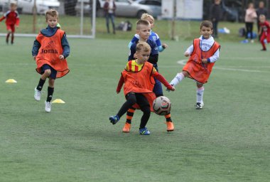ODESSA, UKRAINE - 25 Eylül 2021: Küçük çocuklar, küçük çocuklar spor şampiyonası kasabasında yapay sahada futbol oynuyorlar. Çocuk sporları sağlıklı yaşam tarzıdır. Spor çocukları futbol oyuncuları